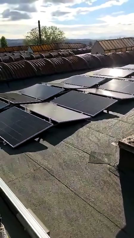 Rânduri de panouri pe acoperișul plat al halei, sub cer cu nori